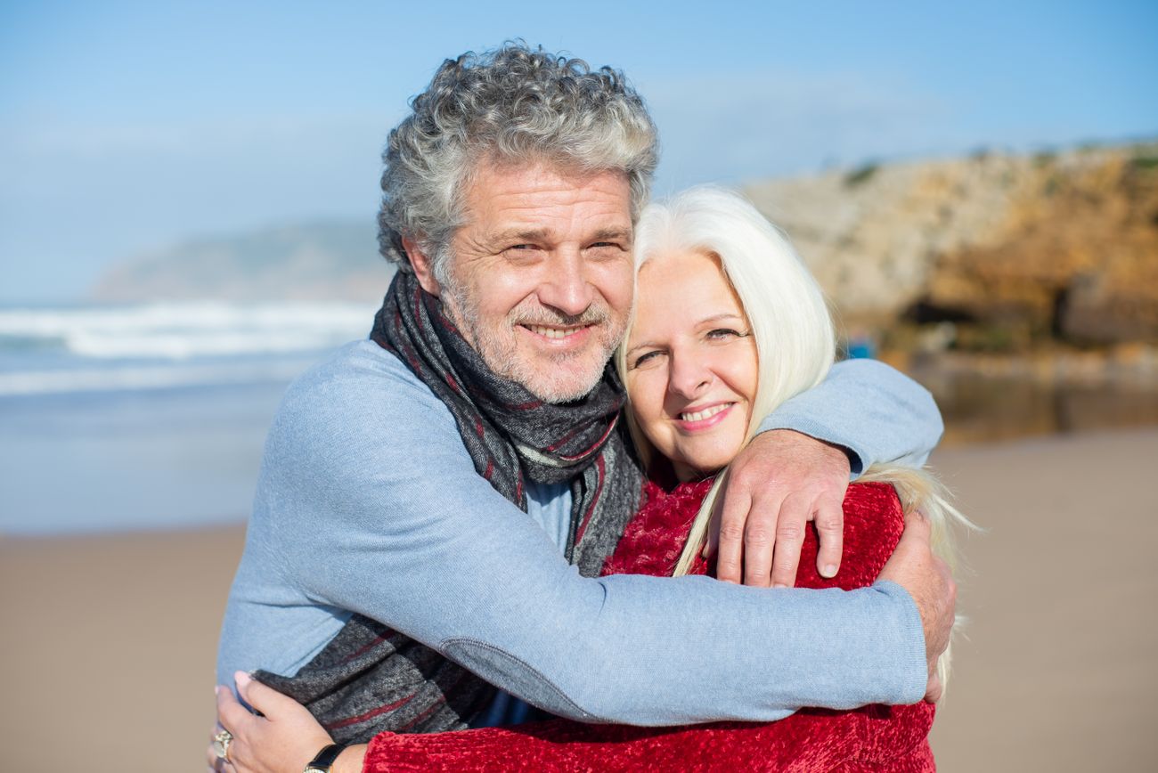 A smiling older couple hugging on a sunny beach