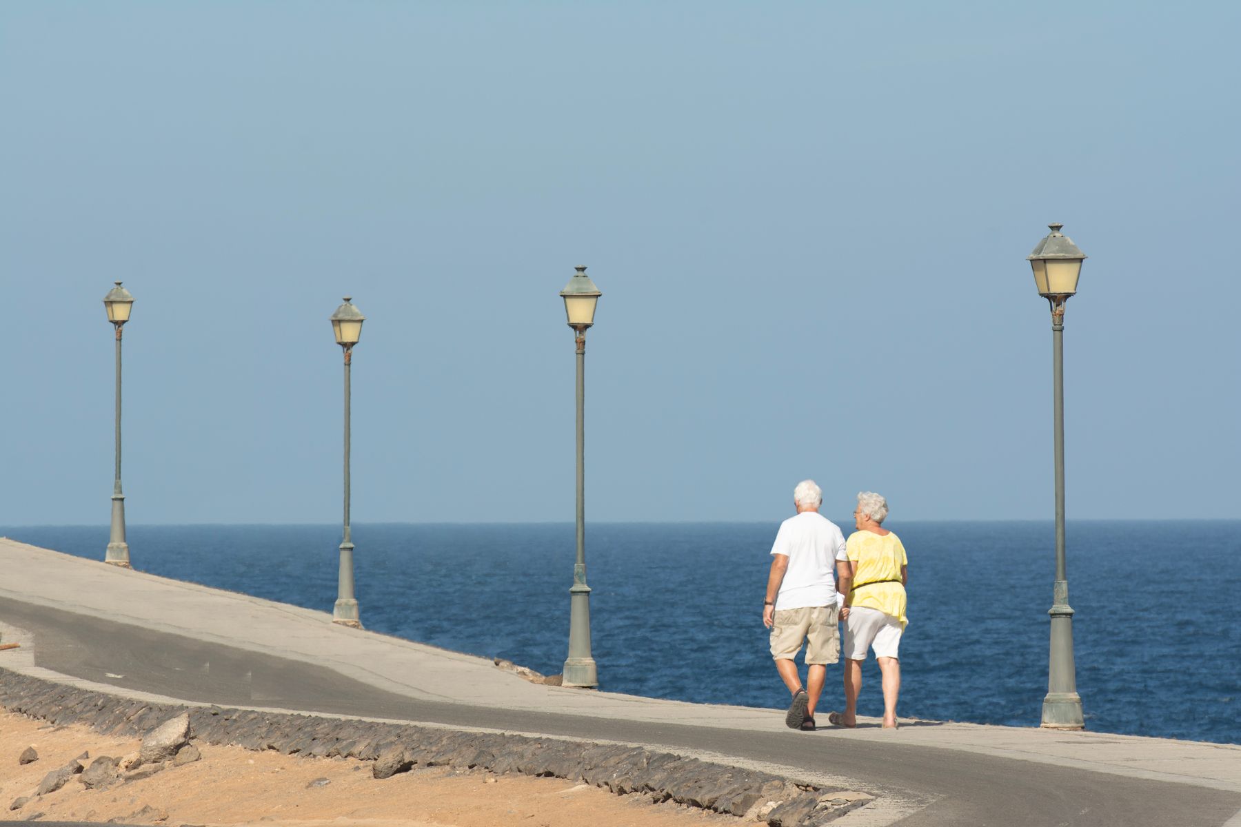 An older couple walking along a seaside promenade
